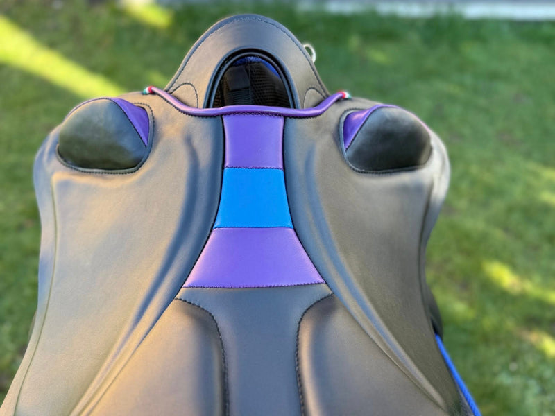 Primo piano dall'alto del seggio e dell'inforcatura di una sella Ghost Endurance in pelle nera, caratterizzata da inserti centrali sedile cocci e profili nei colori viola e blu elettrico.
