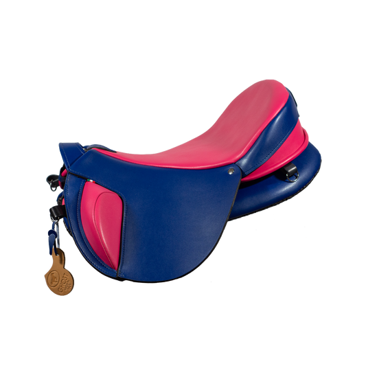 Vista laterale a tre quarti della sella treeless Ghost Quevis Classic Short Flap personalizzata, bicolore blu scuro e rosa acceso, che ne mostra la forma compatta e i blocchi coscia.
